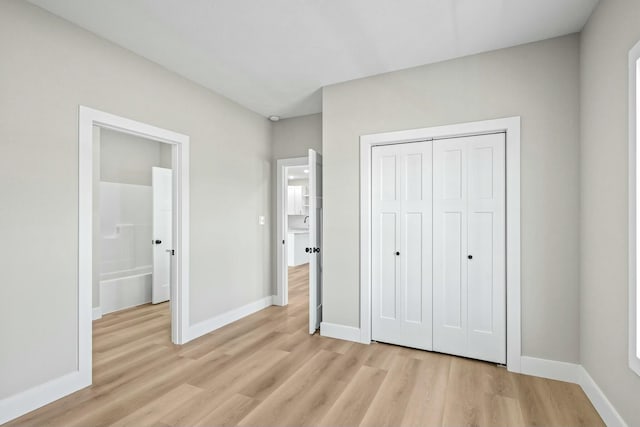 unfurnished bedroom with a closet, baseboards, and light wood-style floors