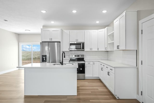 kitchen featuring tasteful backsplash, a sink, appliances with stainless steel finishes, light wood-style floors, and open shelves