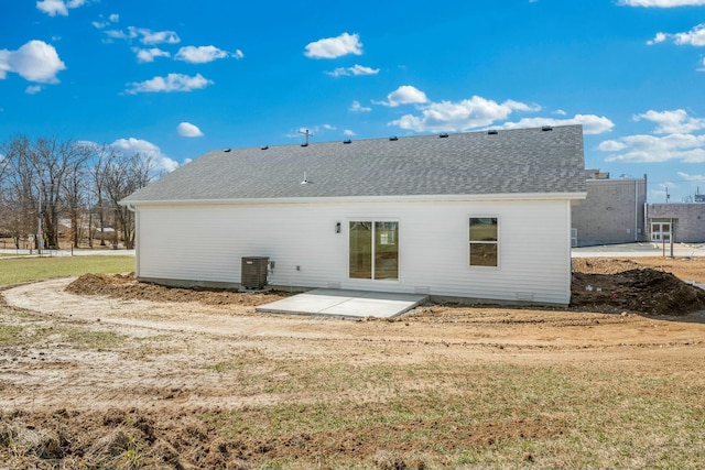 back of house with a patio area, a lawn, a shingled roof, and central AC