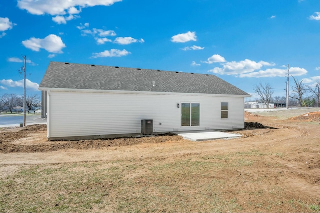 back of property featuring a patio area, central AC unit, and roof with shingles