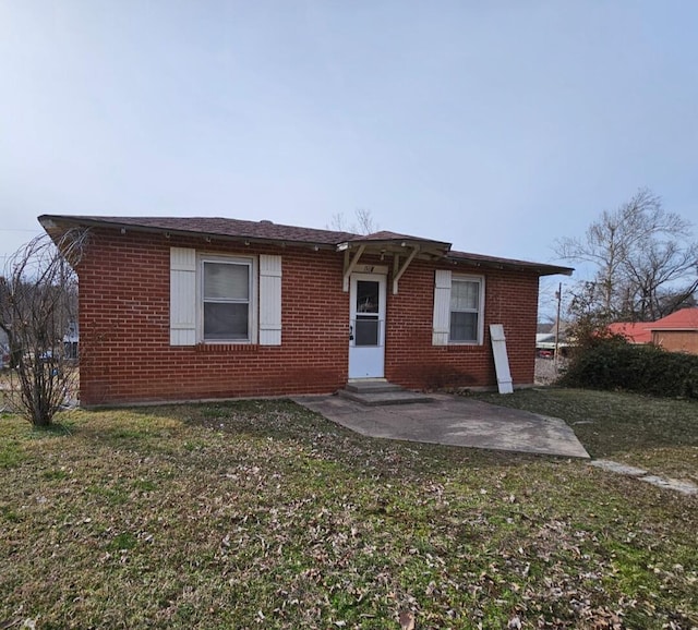 view of front of house featuring a front yard, a patio area, brick siding, and entry steps