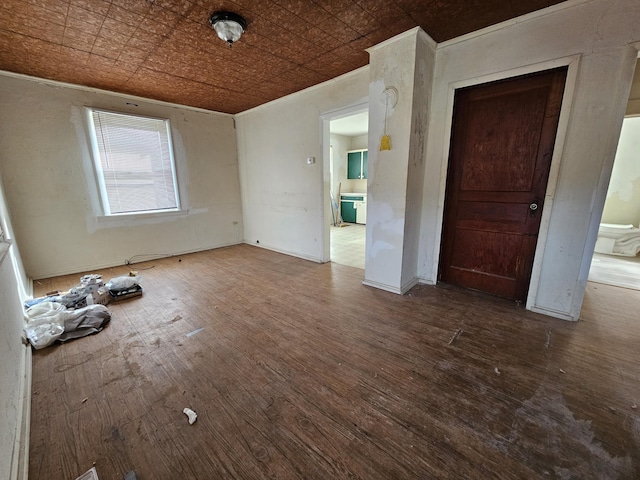 empty room with an ornate ceiling, ornamental molding, and wood finished floors