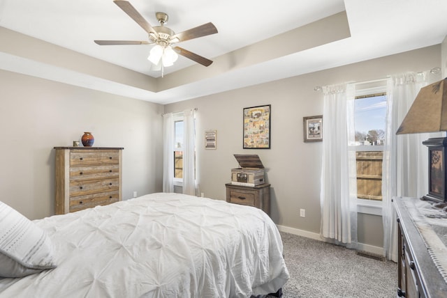 bedroom featuring visible vents, baseboards, a raised ceiling, and light colored carpet