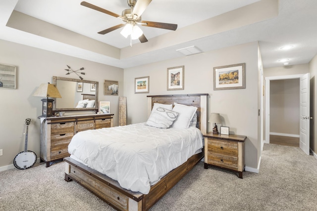 bedroom with light carpet, visible vents, baseboards, a raised ceiling, and a ceiling fan