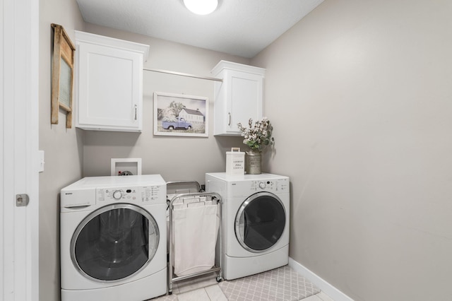 laundry area with light tile patterned floors, independent washer and dryer, cabinet space, and baseboards