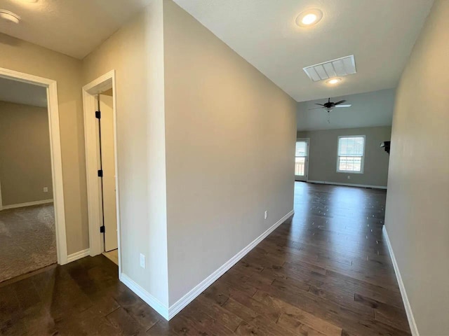 corridor featuring vaulted ceiling, dark wood finished floors, visible vents, and baseboards