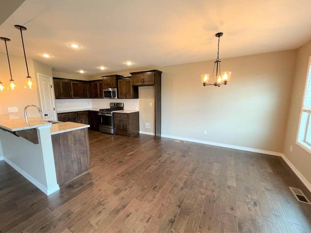 kitchen featuring dark wood finished floors, visible vents, appliances with stainless steel finishes, a sink, and a peninsula