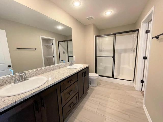 full bathroom featuring double vanity, a shower stall, a sink, and recessed lighting