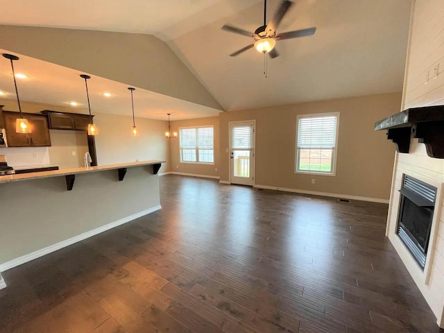 unfurnished living room featuring a fireplace, a ceiling fan, baseboards, vaulted ceiling, and dark wood-style floors