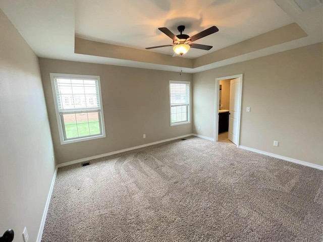 unfurnished bedroom featuring carpet, visible vents, baseboards, and a raised ceiling