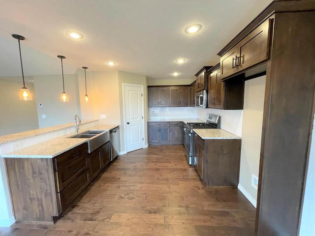 kitchen with stainless steel appliances, a sink, dark brown cabinetry, light wood-type flooring, and a peninsula