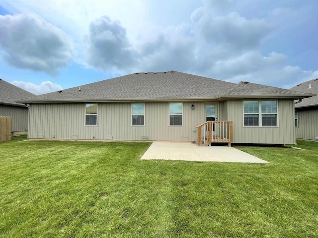 back of property with a patio area, a lawn, and roof with shingles