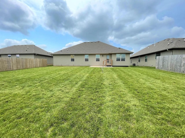 back of property with fence, a lawn, and a wooden deck