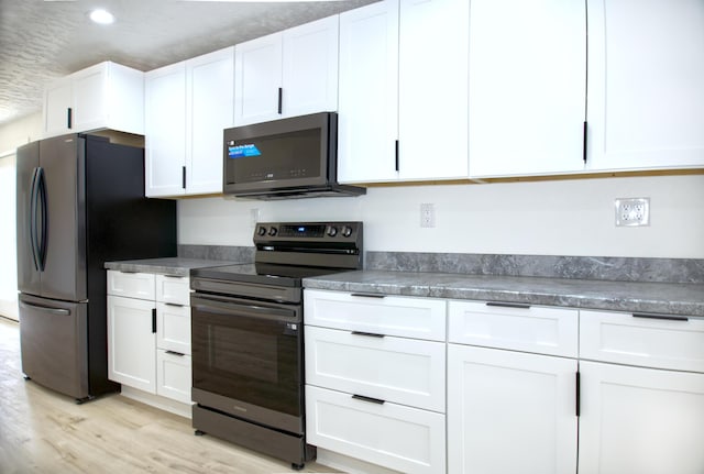 kitchen with stainless steel appliances, white cabinets, and light wood-style floors