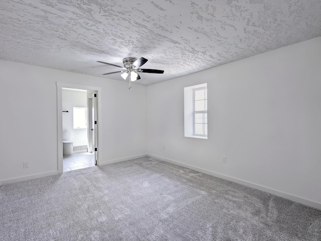 unfurnished room featuring carpet floors, a textured ceiling, baseboards, and a ceiling fan