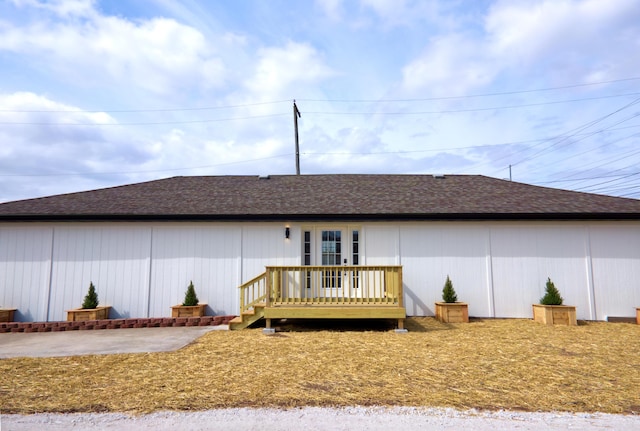 rear view of property featuring roof with shingles and a deck