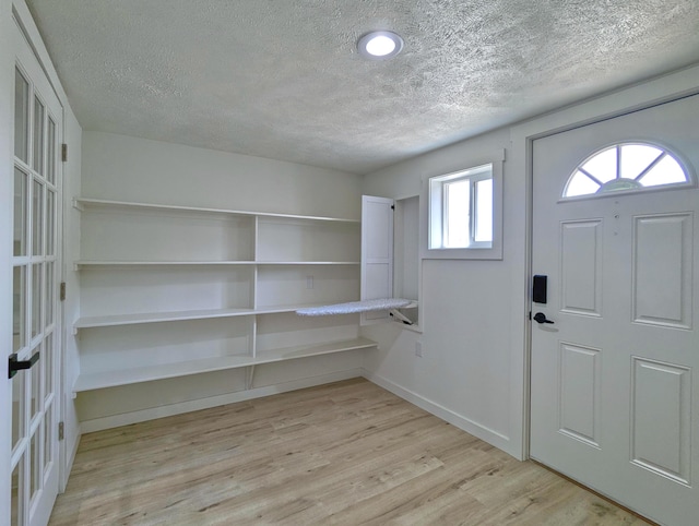 entrance foyer featuring light wood-style floors, baseboards, and a textured ceiling