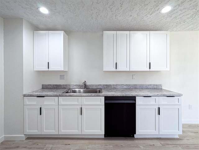 kitchen with dishwasher, light wood finished floors, a sink, and white cabinets