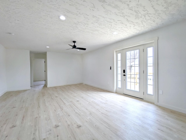 interior space featuring a textured ceiling, ceiling fan, light wood finished floors, and baseboards