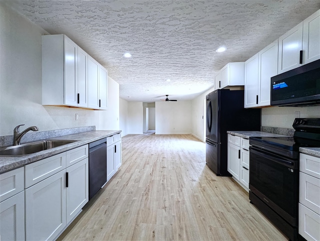 kitchen featuring a sink, white cabinets, stainless steel dishwasher, light wood-type flooring, and black electric range oven