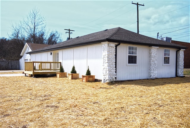 view of side of home featuring roof with shingles and a wooden deck