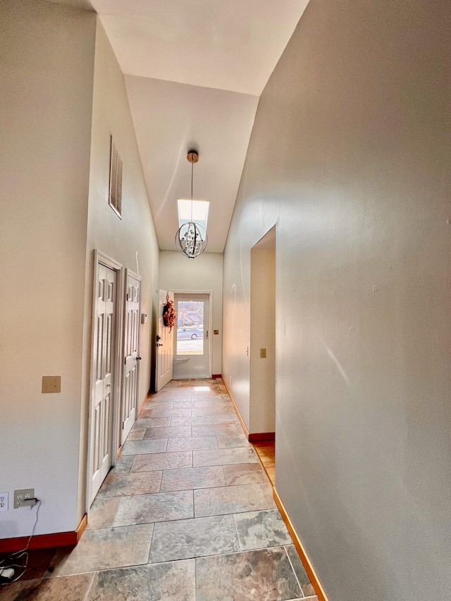 109 Lancashire Dr, Branson, MO 65616 - hallway featuring high vaulted ceiling, visible vents, baseboards, stone tile flooring, and a notable chandelier