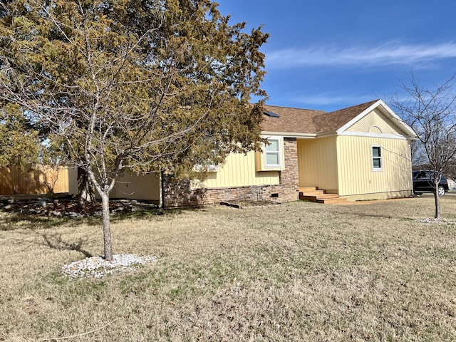 exterior space with roof with shingles, a front yard, crawl space, entry steps, and fence