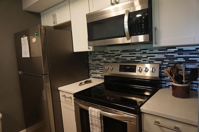 kitchen with appliances with stainless steel finishes, white cabinets, backsplash, and light stone countertops