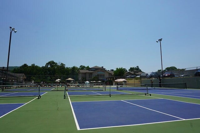 view of tennis court featuring community basketball court and fence