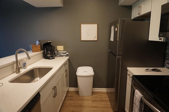 kitchen featuring a sink, white cabinets, light countertops, light wood-type flooring, and stainless steel microwave