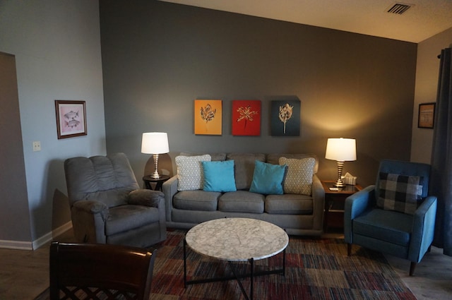 living area with wood finished floors, visible vents, and baseboards