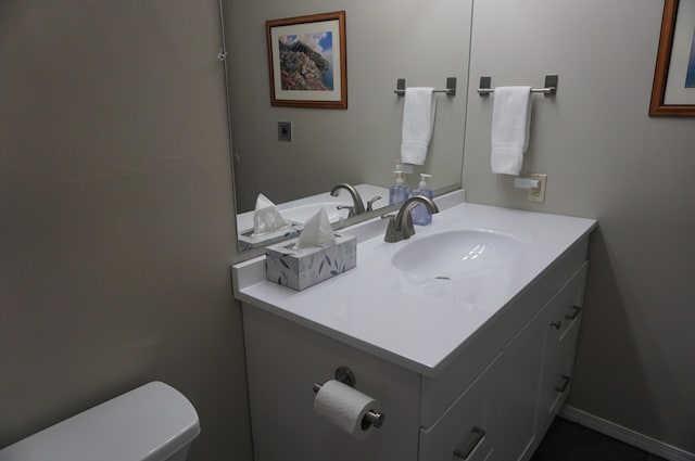 bathroom with toilet, baseboards, and vanity