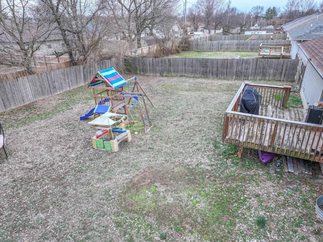 view of yard with a fenced backyard, a deck, and a playground