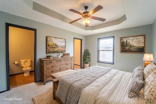 bedroom with light carpet, a raised ceiling, and a ceiling fan