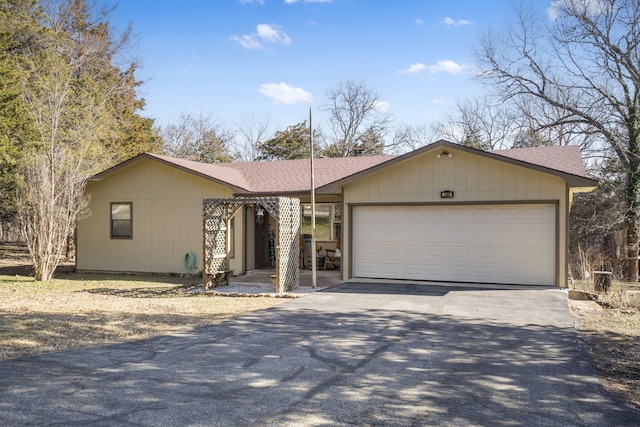 view of front of property featuring a garage, driveway, and a shingled roof