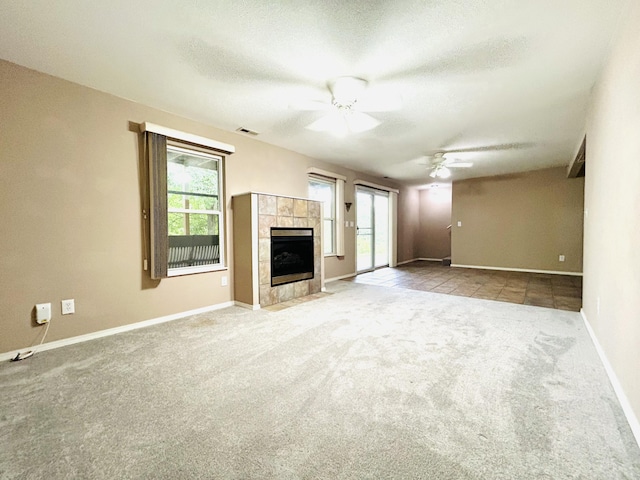 unfurnished living room with a textured ceiling, ceiling fan, a fireplace, visible vents, and carpet