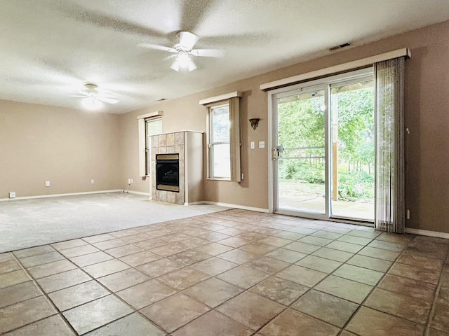 unfurnished living room with baseboards, visible vents, ceiling fan, a textured ceiling, and a fireplace