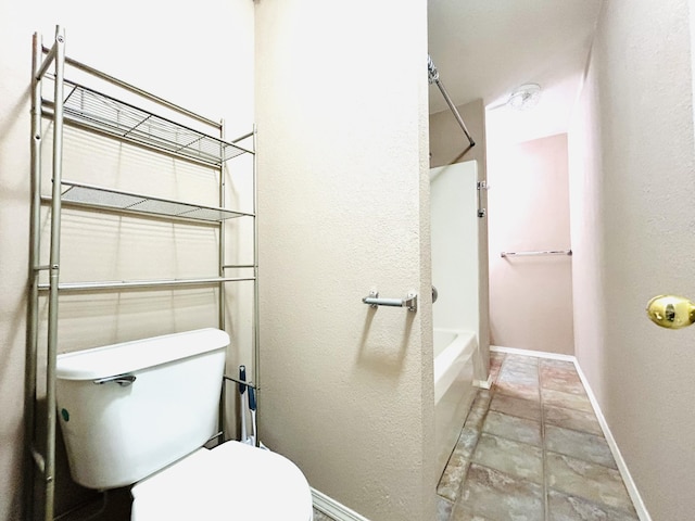 bathroom featuring toilet, baseboards, and shower / bathing tub combination