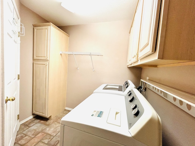 washroom with cabinet space, baseboards, and washing machine and clothes dryer