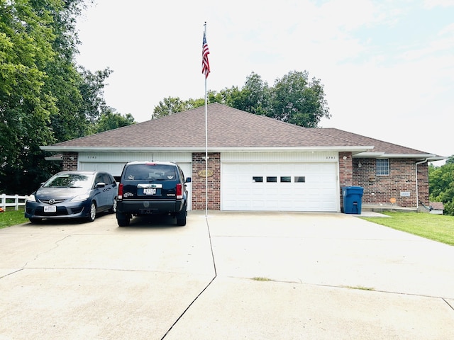 view of side of property with a garage, brick siding, driveway, and roof with shingles