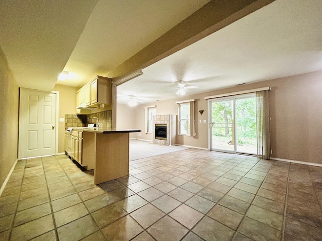 kitchen featuring baseboards, a ceiling fan, open floor plan, and a tiled fireplace