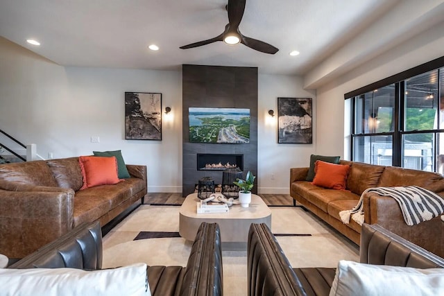 living room with light wood finished floors, baseboards, ceiling fan, a fireplace, and recessed lighting