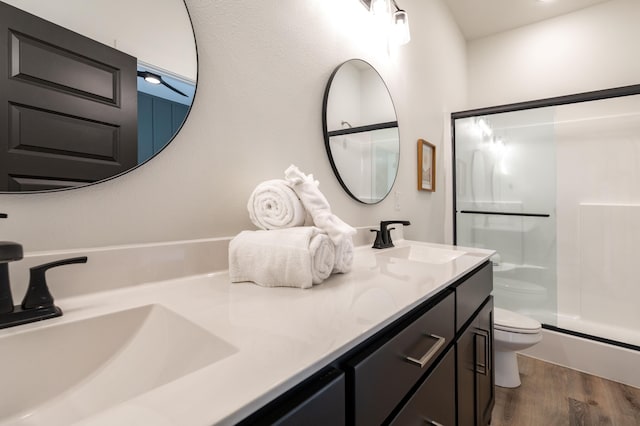 bathroom with toilet, a shower stall, a sink, and wood finished floors