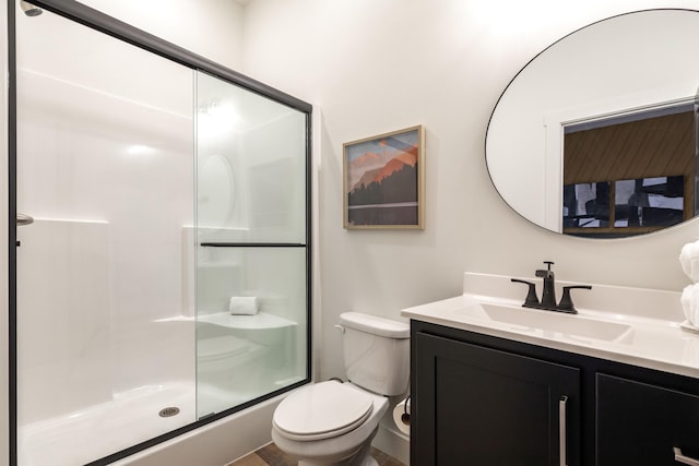 bathroom featuring toilet, a shower stall, and vanity