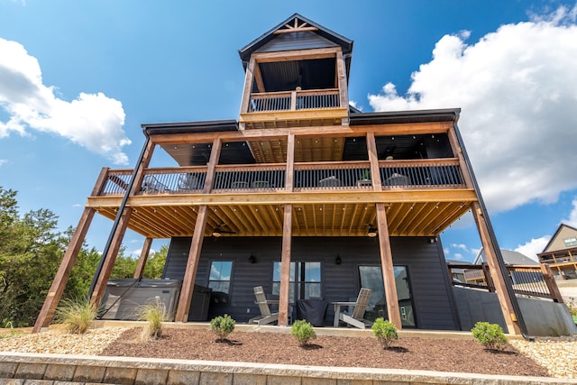 back of property with a hot tub and a wooden deck