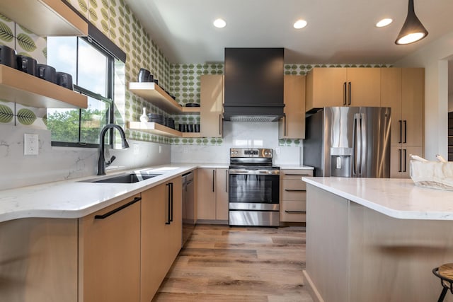 kitchen with light stone counters, custom exhaust hood, stainless steel appliances, open shelves, and a sink