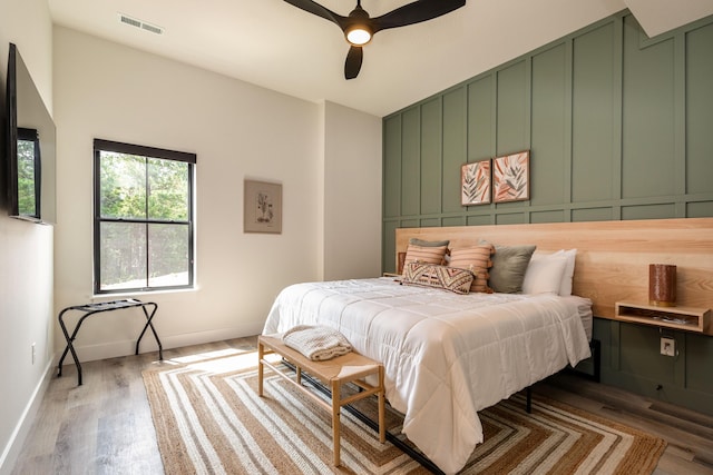 bedroom featuring visible vents, ceiling fan, baseboards, and wood finished floors