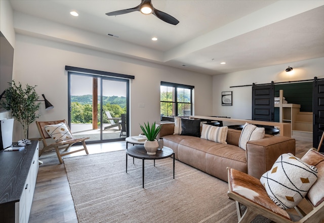 living area with a barn door, a ceiling fan, wood finished floors, and recessed lighting