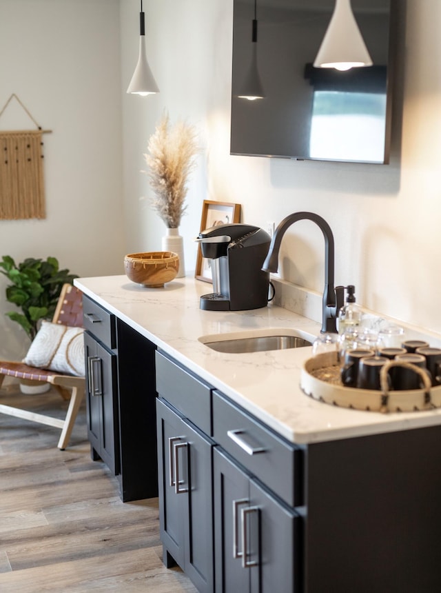 kitchen featuring light stone countertops, light wood-style floors, a sink, and gray cabinetry