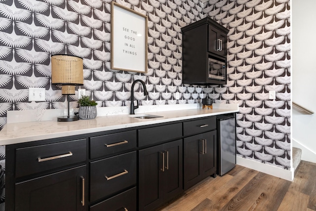 interior space featuring light wood-type flooring, wallpapered walls, wine cooler, and a sink